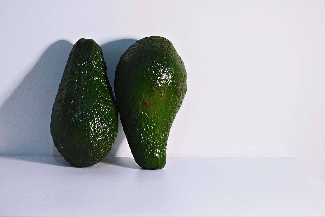 Two fresh avocados on a clean white background, highlighting healthy nutrition.