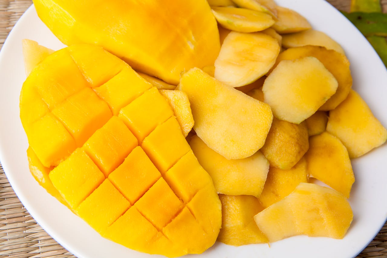 Close-up of ripe peeled mango slices on a white plate showcasing vibrant tropical fruit.